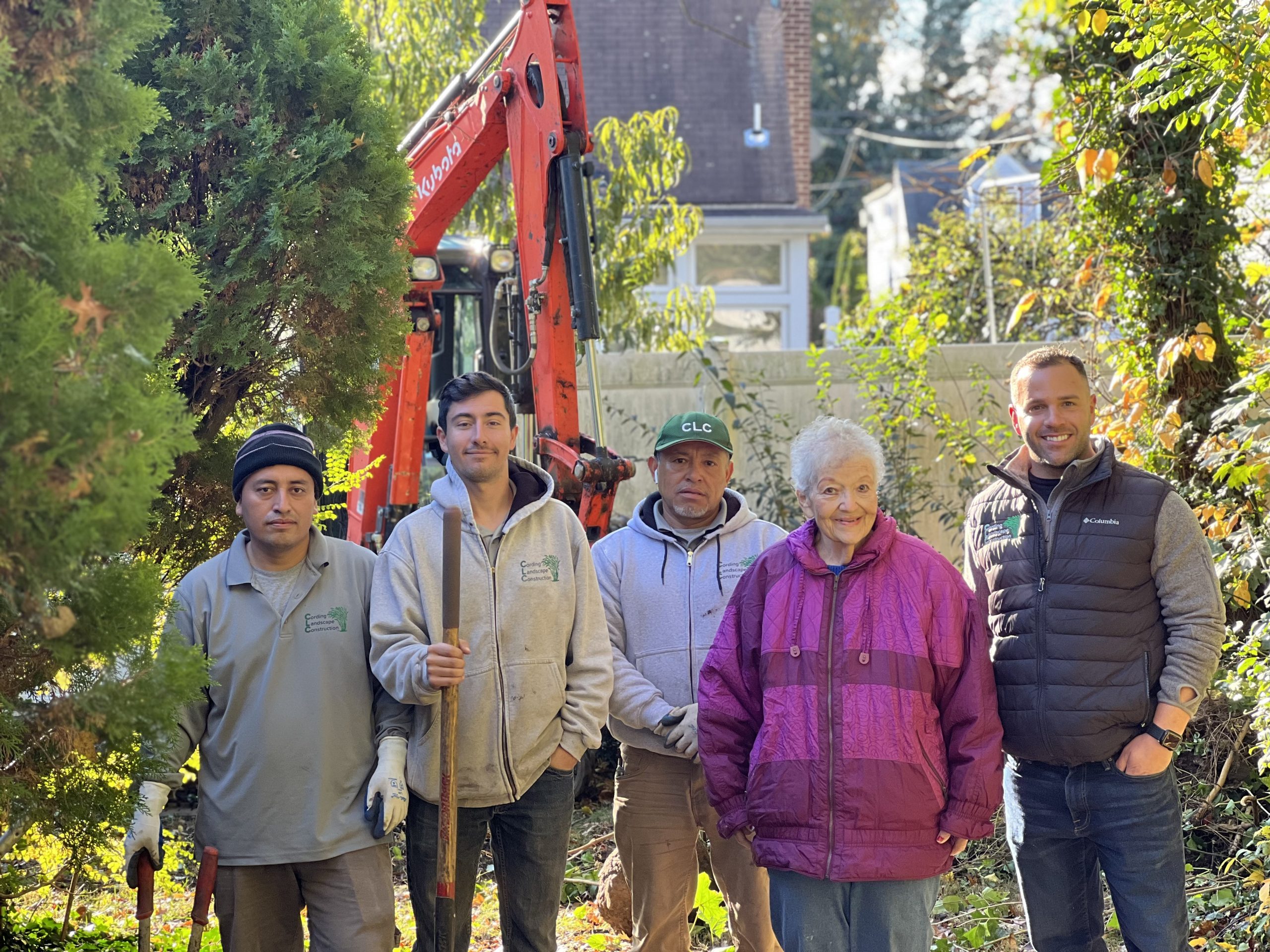 Korean War Veteran Jessie and spouse Debbie standing in their fully transformed front yard in Fair Lawn NJ after a pro bono landscape renovation by CLC Landscape Design coordinated through I Want To Mow Your Lawn